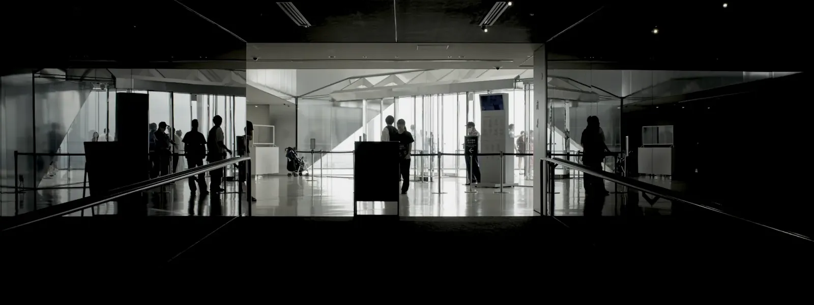 Figures walking through a bright glass lobby
